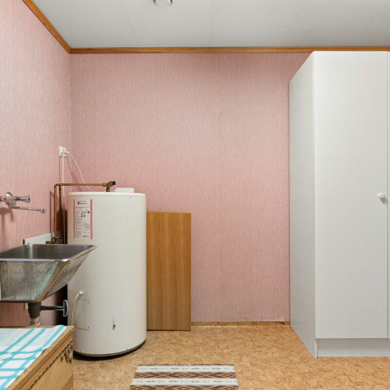 a bathroom with water heater, sink and cabinet